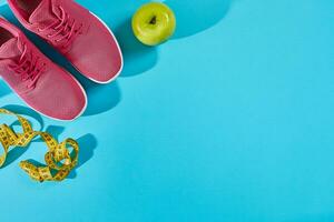sportschoenen met meten plakband Aan cyaan blauw achtergrond. centimeter in geel kleur in de buurt roze sneakers, dichtbij omhoog. foto