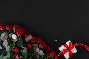 rood rozen, ring en geschenk doos Aan zwart achtergrond foto