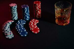 poker chips en wijn glas van cognac Aan donker tafel. het gokken foto