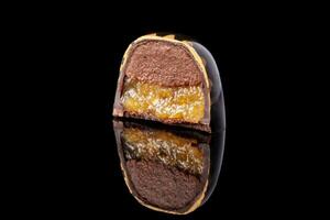 besnoeiing luxe handgemaakt snoep met chocola en geel confituur vulling Aan zwart achtergrond. foto