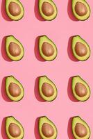 kleurrijk fruit patroon van vers gesneden avocado helften met kuilen Aan koraal roze achtergrond, top visie foto