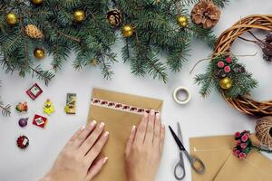 vrouw handen houden vrolijk Kerstmis kaart en envelop. Kerstmis decoratie achtergrond. vlak leggen, top visie. foto