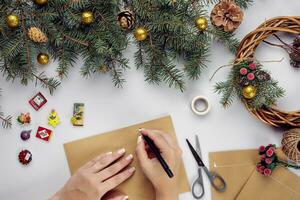 vrouw handen houden vrolijk Kerstmis kaart en envelop. Kerstmis decoratie achtergrond. vlak leggen, top visie. foto