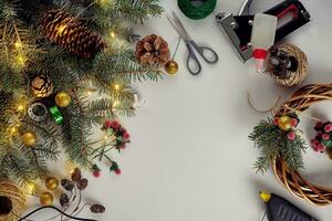 creatief Kerstmis doe-het-zelf. vrouw maken handgemaakt Kerstmis lauwerkrans. huis vrije tijd, hulpmiddelen, snuisterijen en details voor vakantie decoraties Aan wit tafel achtergrond. top visie foto