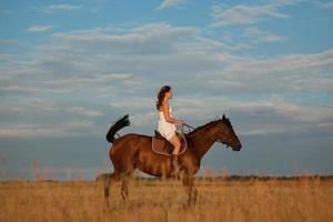 meisje rijdt op een paard in het veld foto