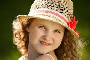 klein gelukkig krullend meisje met een hoed