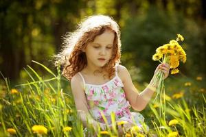 meisje verzamelt een boeket paardebloemen foto