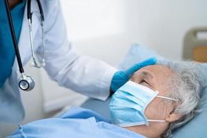 arts helpt aziatische senior patiënt die een masker draagt om het coronavirus te beschermen foto