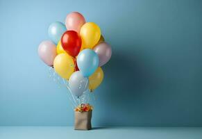 kleurrijk ballonnen bundel gebonden met een geschenk doos Aan een blauw muur achtergrond met kopiëren ruimte. verjaardag, bruiloft, partij of viering concept. gegenereerd ai. foto