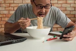 Aziatische mannelijke werknemers zijn druk bezig met het eten van instantnoedels tijdens de lunch.