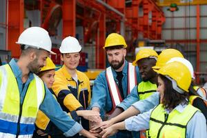 groep van fabriek arbeiders in harde hoeden met gewricht handen samen voor vieren succes foto