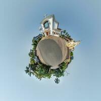 Katholiek kerk in oerwoud tussen palm bomen in Indisch keerkring dorp Aan weinig planeet in blauw lucht, transformatie van bolvormig 360 panorama. bolvormig abstract visie met kromming van ruimte. foto