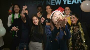 nieuw jaar partij, groep van jong mensen in de kerstman hoeden blazen confetti terwijl vieren nieuw jaar foto