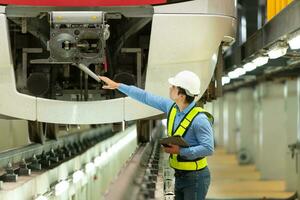 na de elektrisch trein is geparkeerd in de elektrisch trein reparatie winkel, de elektrisch trein ingenieur inspecteert de elektrisch trein motor Bij de voorkant van de processie foto