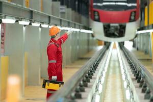 elektrisch voertuig ingenieur met gereedschapskist inspecteren de machinerie van de elektrisch trein volgens naar de inspectie ronde. na de elektrisch trein was geparkeerd in de elektrisch trein reparatie winkel foto