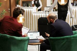 zakenlieden sharing ideeën Bij hotel, vergadering in lounge Oppervlakte lobby naar smederij nieuw zakelijke vennootschap. mensen in pakken bespreken over beheer project Bij belangrijk conferentie, op reis voor werk. foto