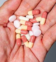 hand- gieten capsules van geneesmiddel nemen farmaceutisch gezondheidszorg behandeling concept, dichtbij omhoog visie kleurrijk pillen en geneesmiddelen in de hand- foto