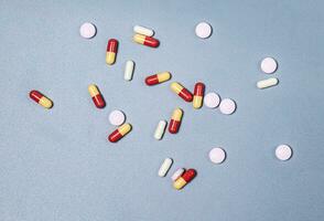 pillen morsen uit tweekleurig capsules pillen geneesmiddelen en voorschrift pillen vlak leggen achtergrond. wit medisch pillen en tablets morsen uit van een drug fles.kopie ruimte voor tekst foto