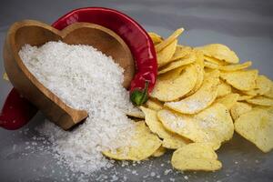 chips met rood peper en besprenkeld zout Aan een grijs achtergrond detailopname. foto