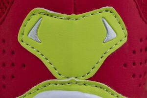 fragment van een rood kleding sneaker met een groen streep. de structuur van de materiaal van sport- schoenen foto