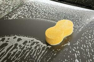 auto schoonmaak en het wassen met geel spons en schuim zeep foto