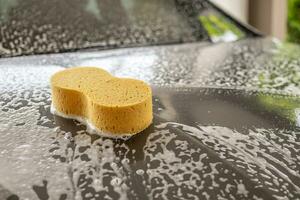 auto schoonmaak en het wassen met geel spons en schuim zeep foto