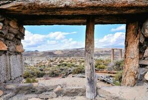 een oud venster in een verlaten gebouw met een visie van de woestijn foto