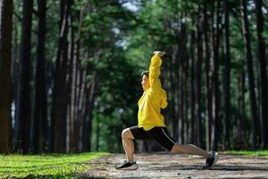 spoor loper is uitrekken voor warm omhoog buitenshuis in de pijnboom Woud aarde weg voor oefening en training activiteiten opleiding voor bereiken gezond levensstijl en geschiktheid foto