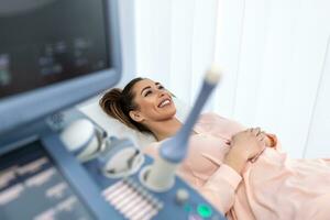 gelukkig zwanger vrouw bezoekende vrouwen dokter in de moederschap centrum, aan het doen echografie scannen, bezorgd over de Gezondheid van de kind, gezond moederschap concept foto