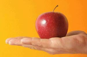 een hand- Holding een appel Aan een oranje achtergrond foto