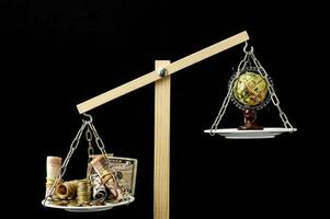 een balans schaal met geld en een wereldbol foto