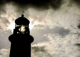 de silhouet van een vuurtoren tegen de wolken foto