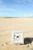 een klok in de zand Aan een strand foto