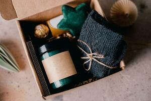 Kerstmis doos met presenteert - kaars in donker kan, chocola snoepjes, knus grijs sokken en feestelijk decoratie. gepersonaliseerd ambacht doos voor winter vakantie foto