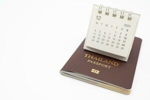 gemakkelijk bureau kalender voor december 2023 en paspoort. kalender en vakantie concept met paspoort isoleren Aan wit achtergrond. foto