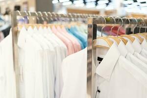 rek met schoon overhemden in vervagen boodschappen doen winkelcentrum achtergrond. kleren hanger. foto