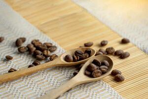 geroosterd koffie bonen in houten lepel en verspreiding Aan geweven bamboe onderzetter. het is een medium gebraden met medium intensiteit koffie smaak. een beetje zoet en zuur, geschikt voor beide heet en verkoudheid koffie. foto