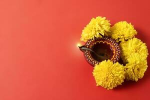 gelukkig diwali en kartika deepam festival groeten - kleurrijk klei deepam met geel bloemen Aan rood achtergrond foto