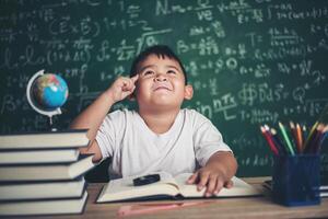 nadenkende kleine jongen met boek in de klas foto