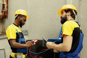 doeltreffend technici in opdracht naar Doen condensor controleren, bijvullen freon. gekruid mechanica gebruik makend van professioneel verdeelstuk meters naar precies meten de druk in buiten lucht conditioner foto