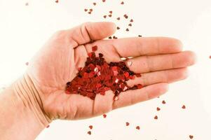 een hand- Holding een handvol van rood confetti foto