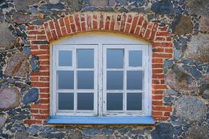 dichtbij omhoog venster. de muur van een steen oud huis. foto