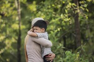 portret van moeder en zoon gelukkig knuffelen samen in het park. foto