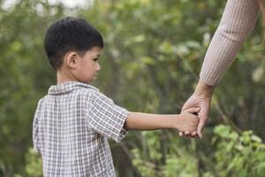 close-up van gelukkige moeder en zoon hand in hand in een park. familie begrip. foto