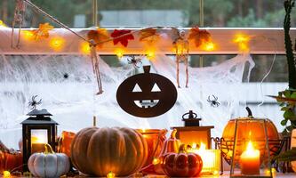 feestelijk decor van de huis Aan de vensterbank voor halloween - pompoenen, jack O lantaarns, schedels, spinnenwebben, spinnen, skeletten, kaarsen en een slinger - een knus en vreselijk humeur foto