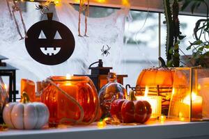 feestelijk decor van de huis Aan de vensterbank voor halloween - pompoenen, jack O lantaarns, schedels, spinnenwebben, spinnen, skeletten, kaarsen en een slinger - een knus en vreselijk humeur foto