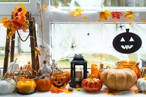 feestelijk decor van de huis Aan de vensterbank voor halloween - pompoenen, jack O lantaarns, schedels, spinnenwebben, spinnen, skeletten, kaarsen en een slinger - een knus en vreselijk humeur foto