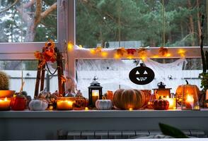 feestelijk decor van de huis Aan de vensterbank voor halloween - pompoenen, jack O lantaarns, schedels, spinnenwebben, spinnen, skeletten, kaarsen en een slinger - een knus en vreselijk humeur foto