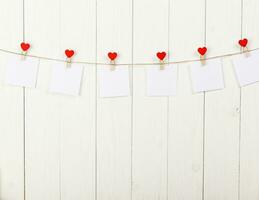 wit stukken van papier Aan wasknijpers met een hart Aan een houten achtergrond foto