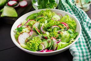 gezond veganistisch voedsel. vegetarisch groente salade van radijs, komkommers, sla en rood ui. foto